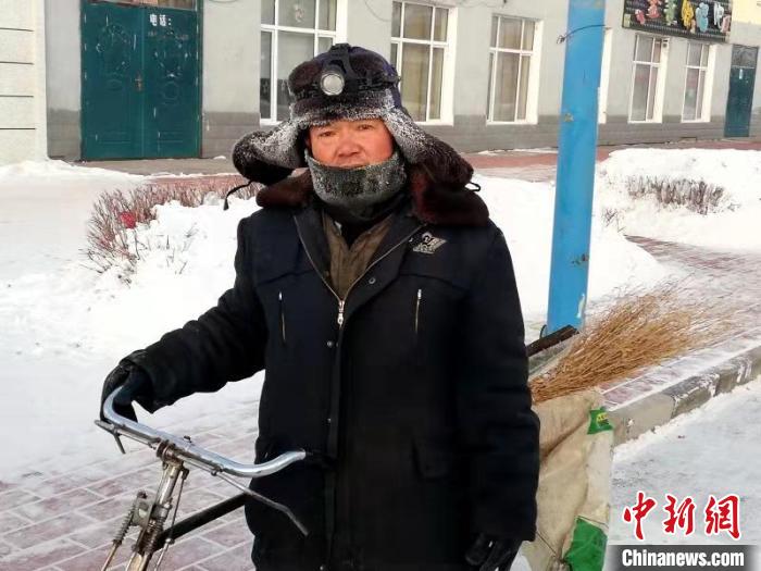 冻得满脸通红的环卫工人推着自行车清扫街道卫生。　冯宏伟 摄